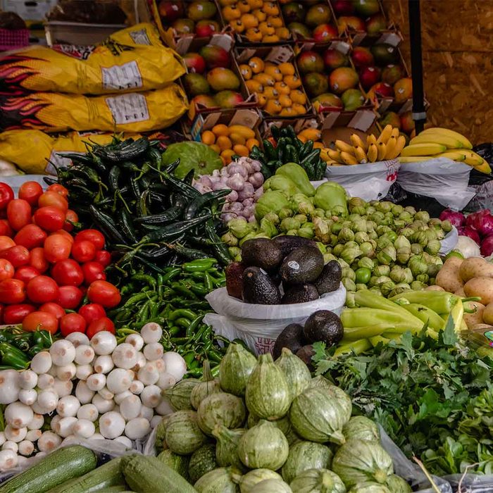 Puesto de frutas y verduras frescas, incluyendo mangos, tomates y aguacates